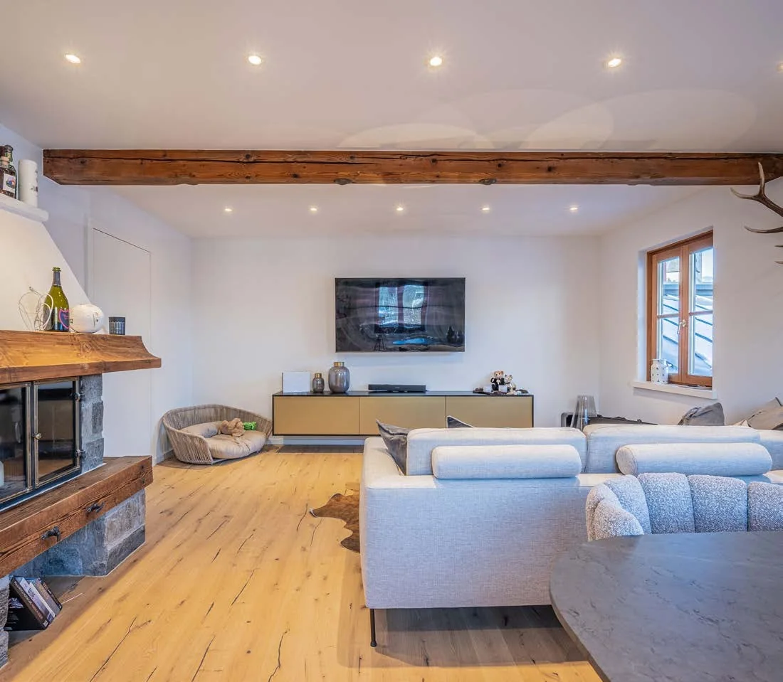 Wohnbereich mit Kamin aus Stein und Holz, Sofa und Esstisch